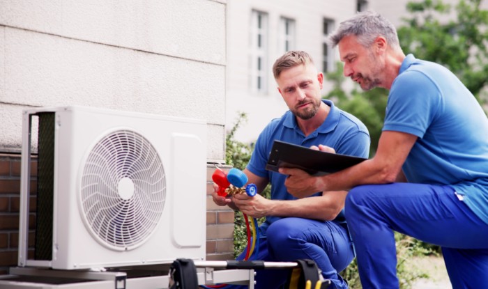 HVAC technicians reviewing an outdoor air conditioning unit in Flagstaff, AZ